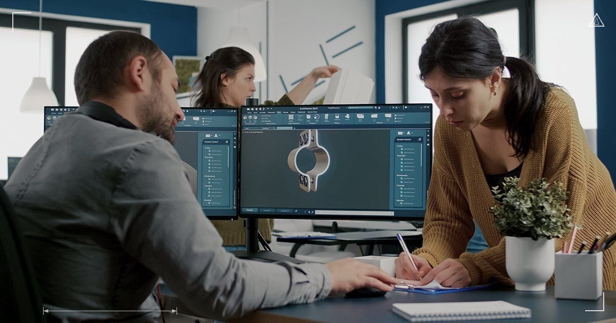 SolidWorks benzeri CAD yazılımında metal kelepçe modeli üzerinde çalışan mühendis ekip ve çift monitörlü iş istasyonu